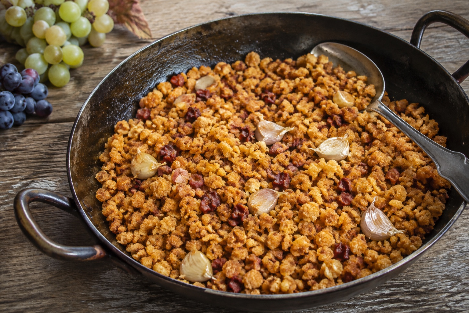Sartén compartida de migas manchegas con ajos y uvas