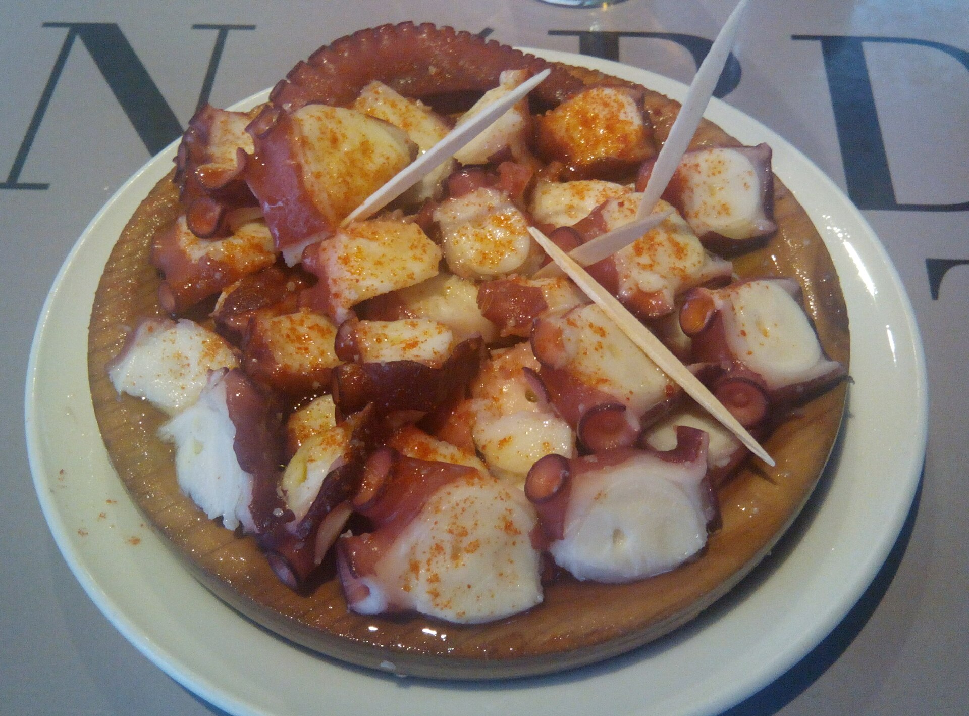 Ración real de pulpo á feira servida en un plato de madera