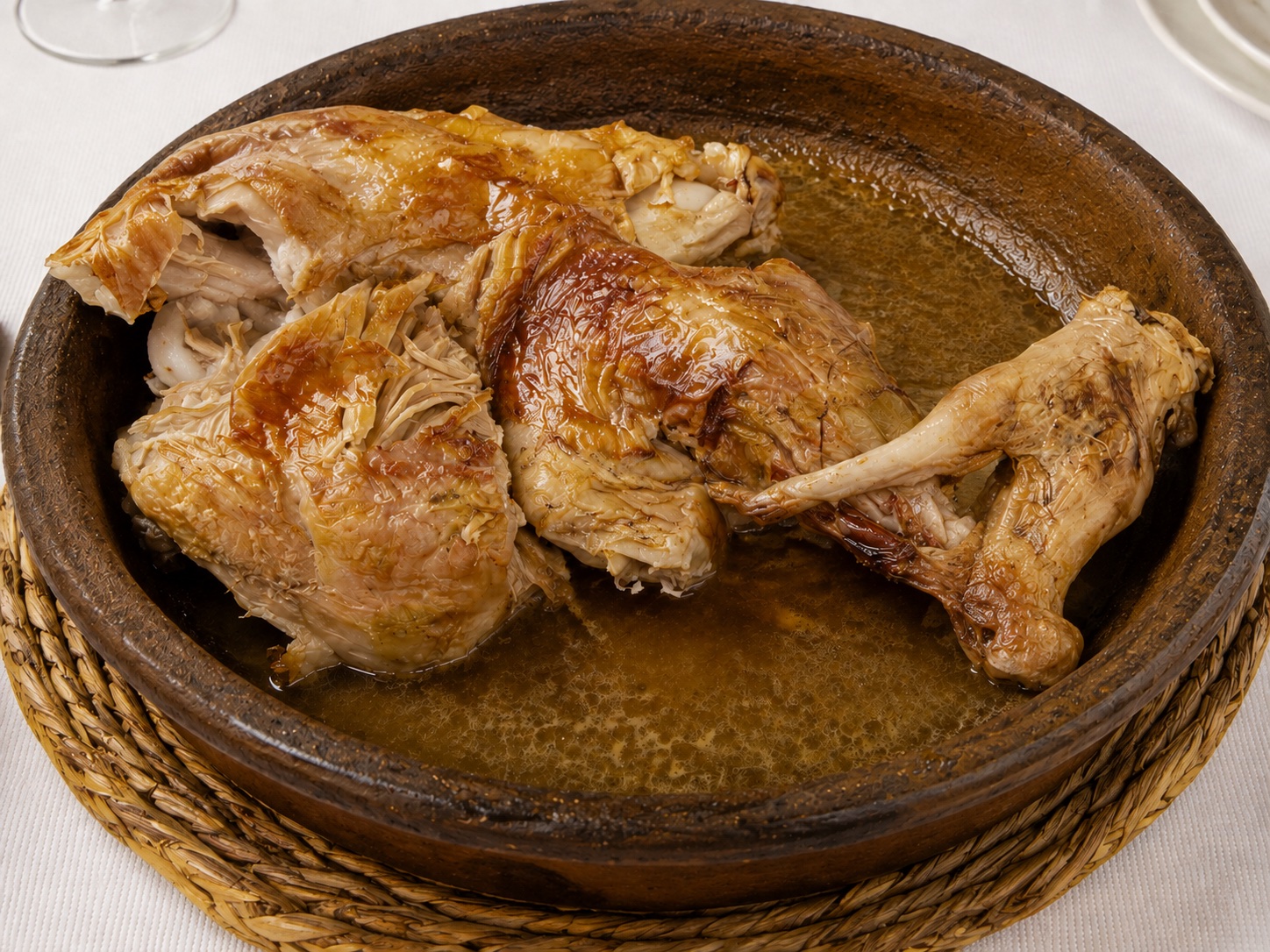Lechazo asado servido en una cazuela de barro